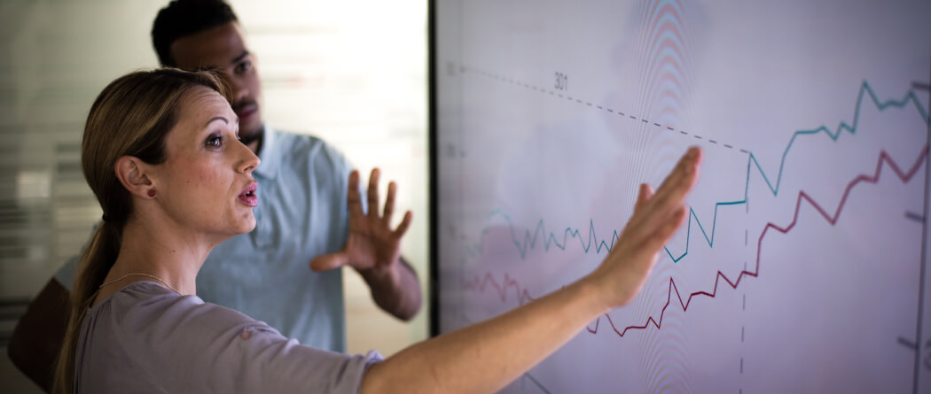 Woman pointing at a graph on a large screen